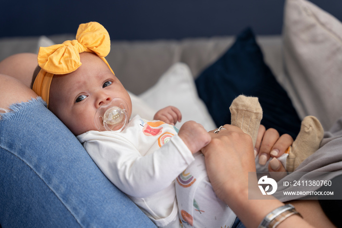 Portrait of baby girl sitting on mother laps at home