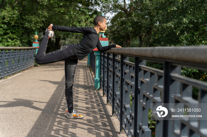 Athletic woman stretching leg on footbridge in park