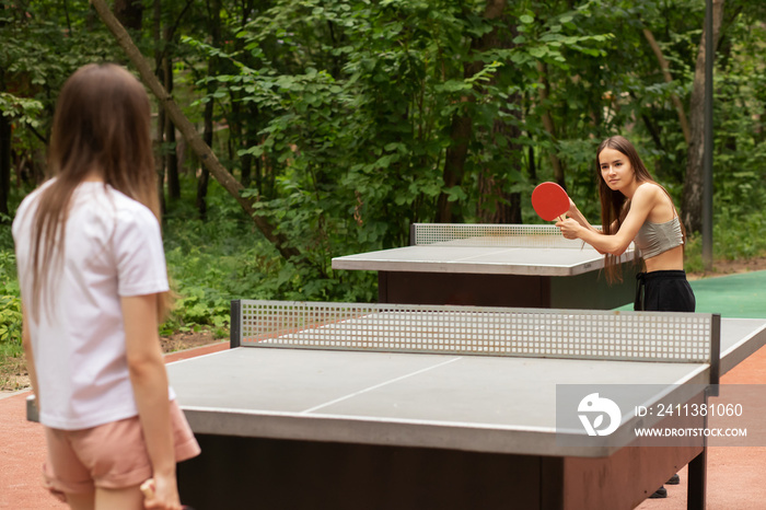 ping pong outdoor, teenager girls playing table tennis with table tennis rackets and ping pong ball