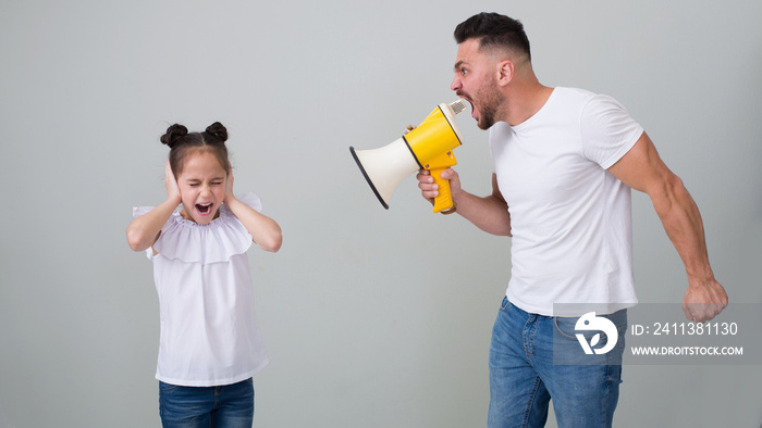 Scared abused girl closing her ears, hiding from dad who screaming at her