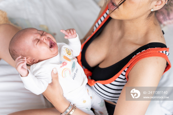 Mother consoling newborn baby girl in bed at home