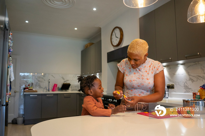 Mother and daughter (2-3) preparing food in kitchen