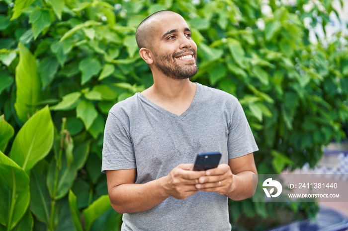 Young latin man smiling confident using smartphone at park