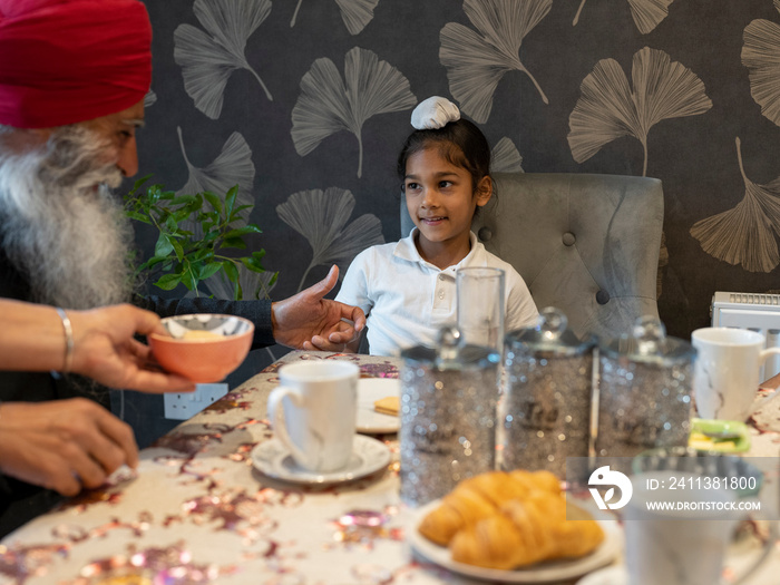 Grandfather and grandson (6-7) having afternoon tea at home