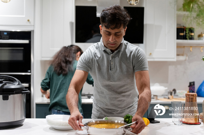 Man putting pot on table in kitchen