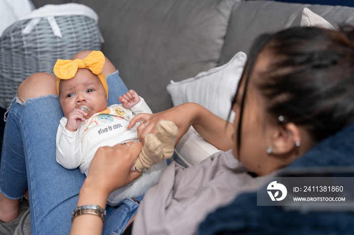 Mother relaxing with baby girl on sofa at home