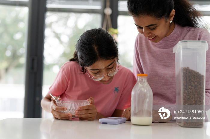 Mother and daughter using phone during breakfast