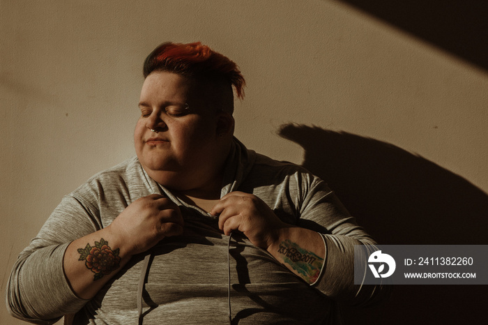 portrait of a plus size woman with hands on shirt face to sun