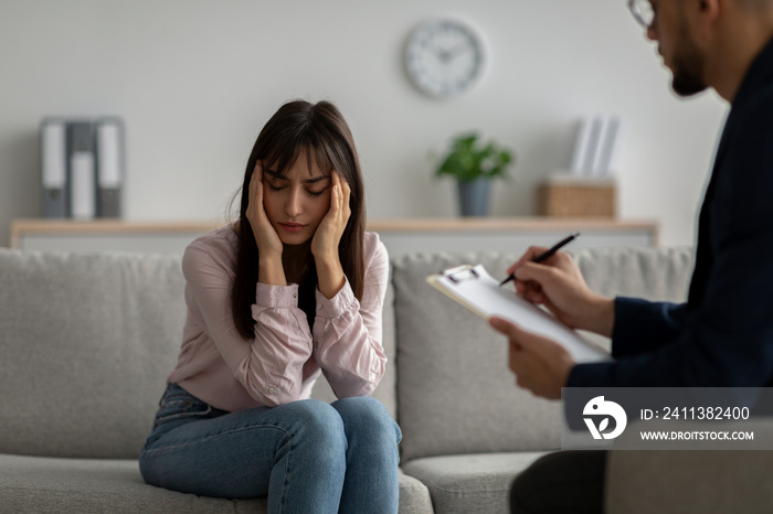 Depressed arab woman suffering from nevrous breakdown or depression, having session at psychologist’s office