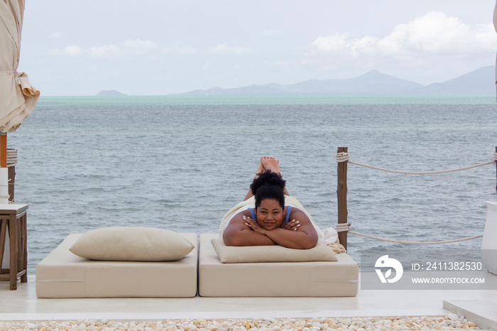 Young woman relaxing on sun lounger near bay