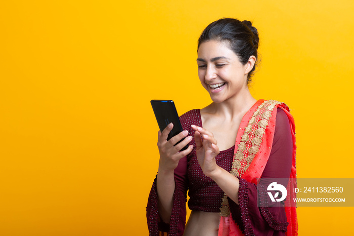 Portrait of young adult indian woman in sari message text sms with mobile phone.