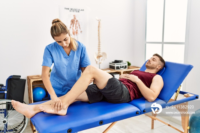 Young hispanic physioterapist woman make ankle rehab treatment to man at the clinic.