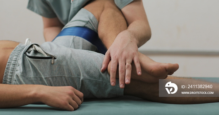 Physiotherapist working with a male patient. He stretching male patient on the bed in hospital