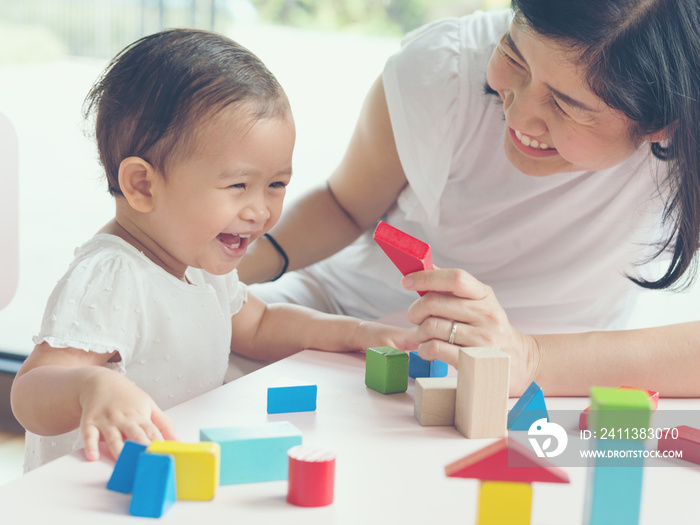 Asian mom and girl kid playing with blocks. Vintage effects and soft light.