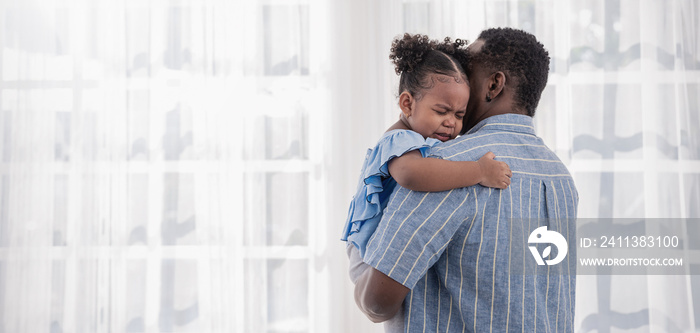 Portrait of american african father daughter hugging laughing in living room. addy and cry little girl spending leisure time at home. Single dad, family lifestyle father’s day concept banner