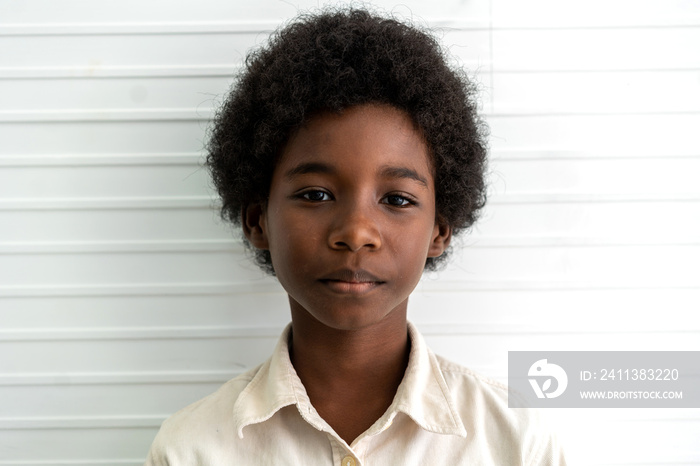 Portrait of black african american cute little boy child sitting on floor on white wall background