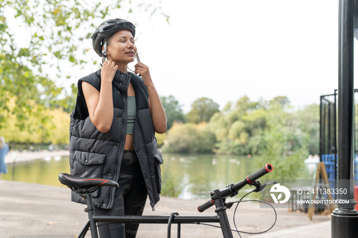 Woman fastening bike helmet in park