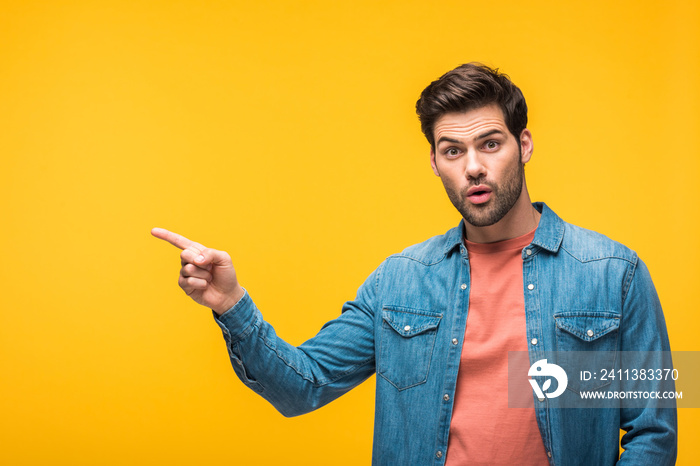 surprised handsome man pointing with finger Isolated On yellow