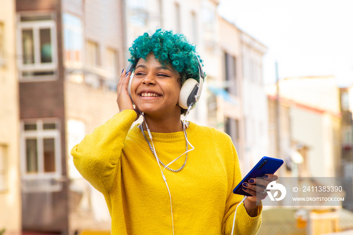 young girl with mobile phone and headphones outdoors in the city