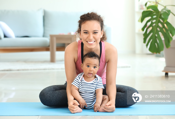 African-American mother training with cute little baby at home