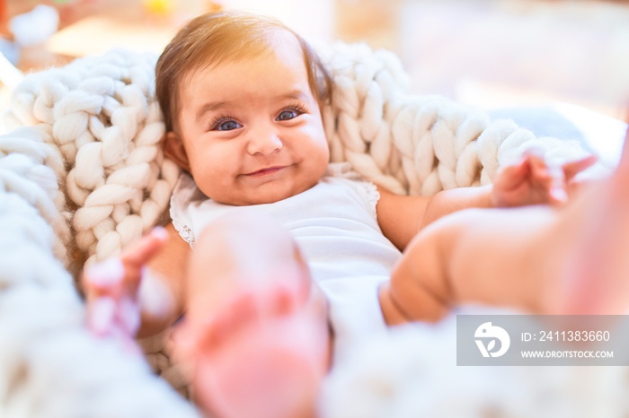 Beautiful infant happy at kindergarten around colorful toys lying inside crib