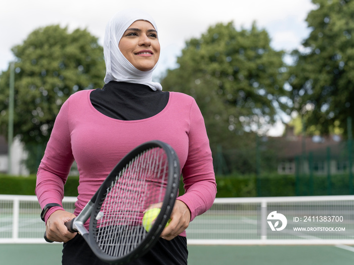 UK,Sutton,Portrait of smiling woman in headscarf at tennis court