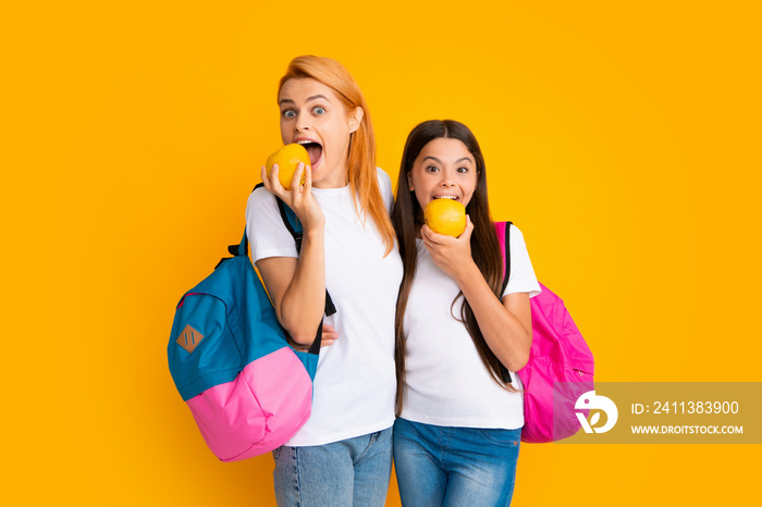 Back to school. Mother and daughter teen girl in with backpack. Teenagers students on yellow isolated background. Mom and child go school.