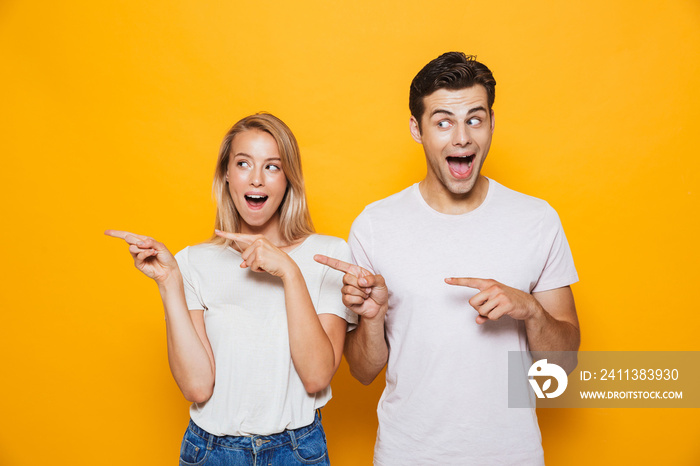 Happy excited young loving couple pointing.