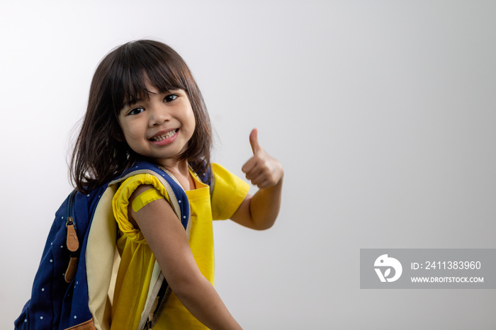 Asian young girl showing her arm with yellow bandage after got vaccinated or inoculation, child immunization, covid delta vaccine concept