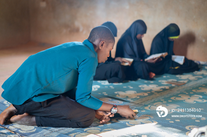 African teenage boys and girls sitting and reading book in poor school, high quality photo