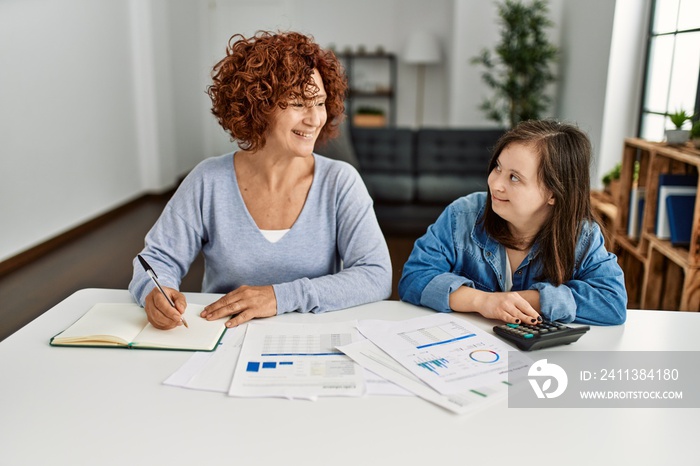 Mature mother and down syndrome daughter doing economy house together