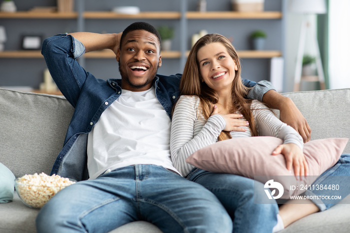 Couple’s Leisure. Happy Interracial Lovers Watching Tv And Eating Popcorn At Home