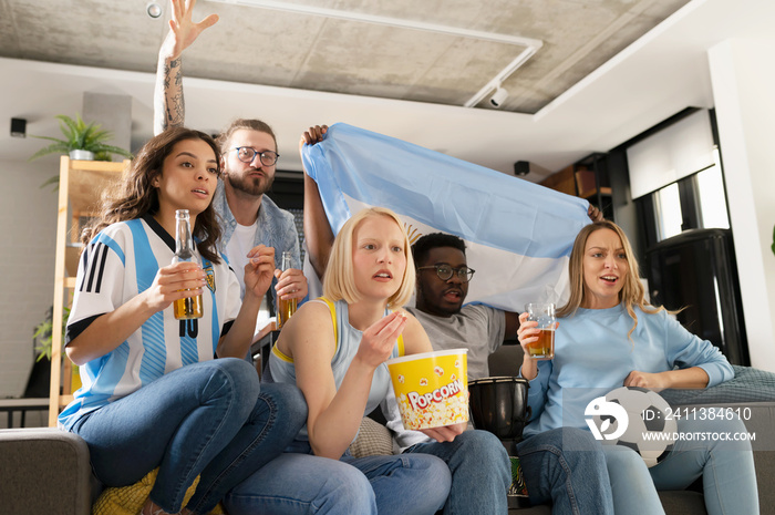 Excited multicultural football fans celebrate a goal score of their team. Friends gathered together to watch the soccer football championship