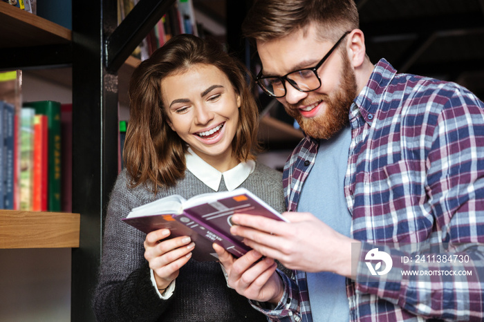 Two happy students working in library with books together