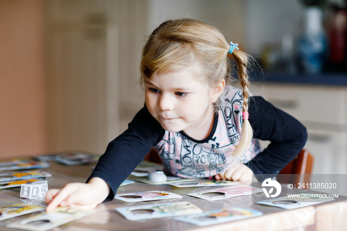 Adorable cute toddler girl playing picture card game. Happy healthy child training memory, thinking. Creative indoors leisure and education of kid during pandemic coronavirus covid quarantine disease