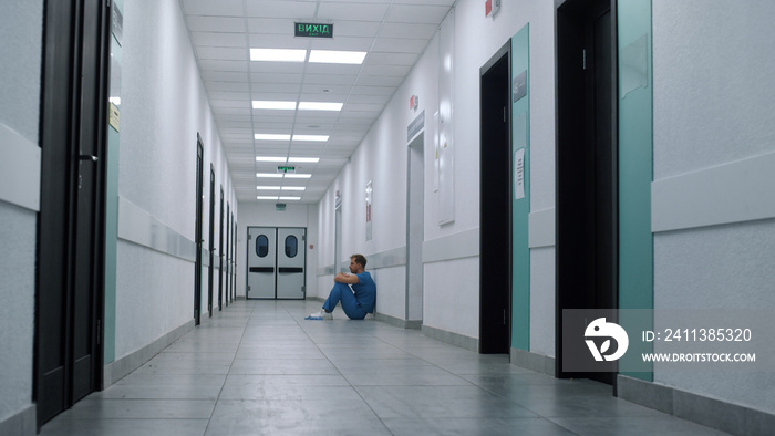 Medicine worker sitting floor ambulance hallway. Medic resting after surgery.