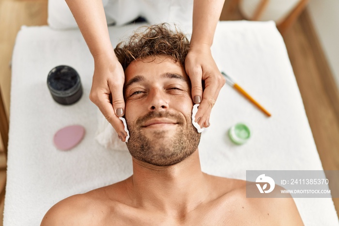 Young hispanic man having facial treatment at beauty center