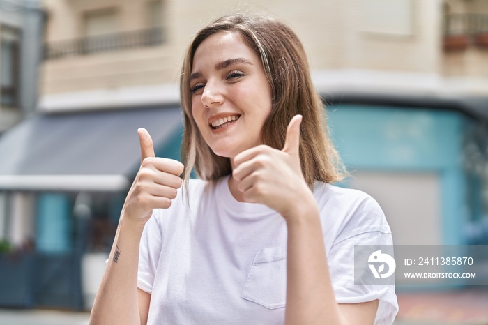 Young woman smiling confident doing ok sign with thumbs up at street