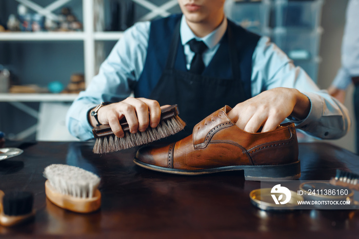 Shoemaker wipes black shoe polish, footwear repair