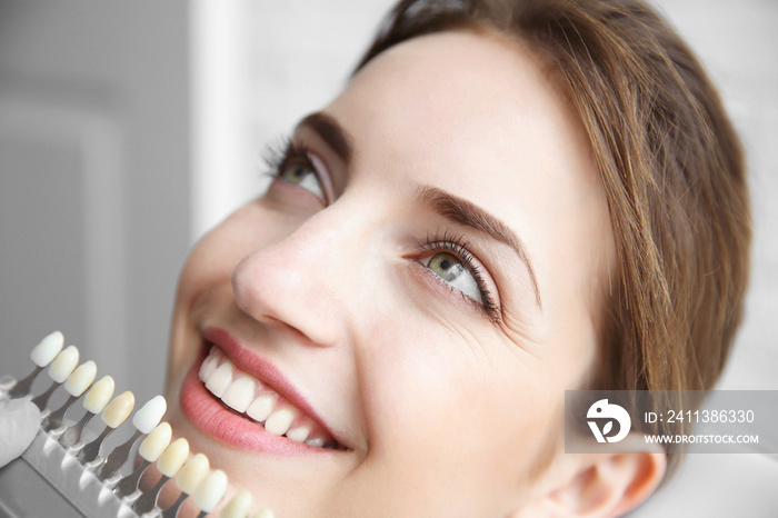 Young woman choosing color of teeth at dentist