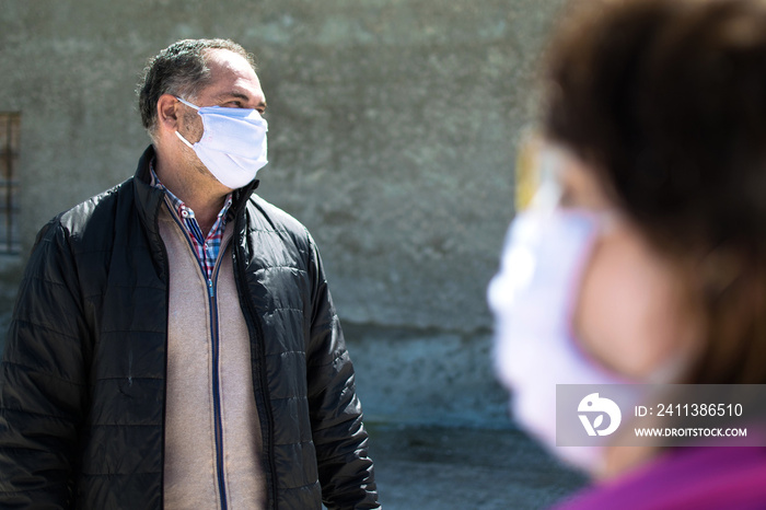 Two people talking keeping security distance, wearing protection mask for coronavirus or covid-19 virus outbreak in a city. Corona virus, Covid-19, virus outbreak or social distancing concept.