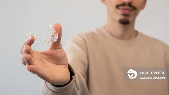 Man holds invisalign transparent braces for dental correction. Dentist office