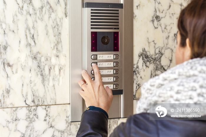 Woman pushing the button and talking on the intercom