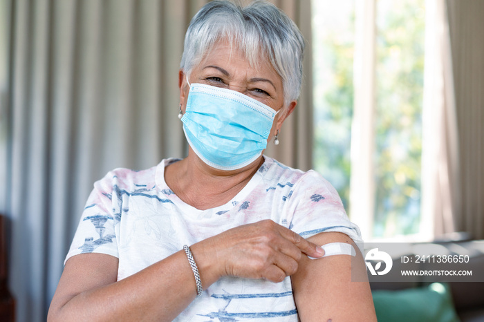 Senior caucasian woman in face mask showing plaster after vaccination