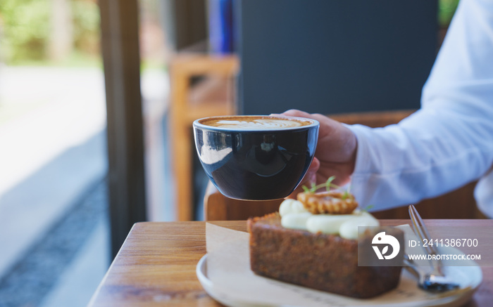 Closeup image of a woman holding and drinking coffee with a piece of carrot cake on the table