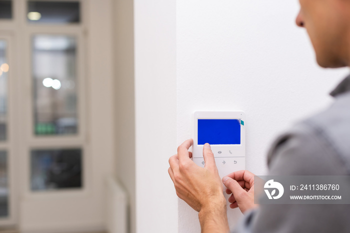 Man installing security alarm system on light wall at home, closeup