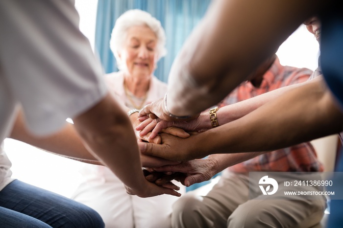 Cropped image of female doctor and senior people stacking hands