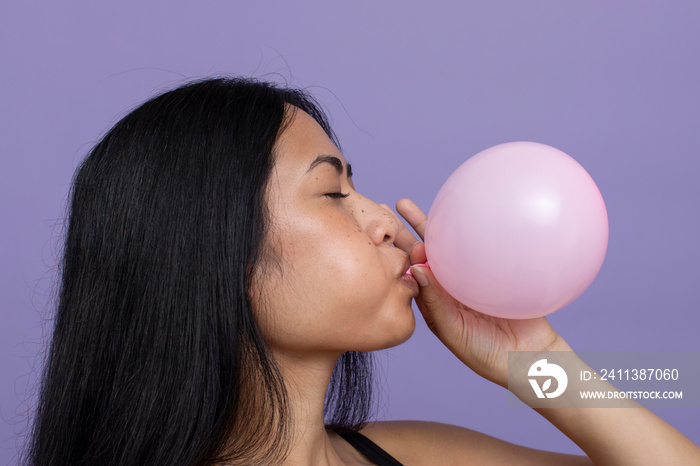 Woman with black hair blowing pink balloon