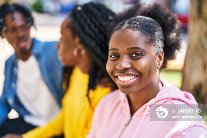 African american friends smiling confident sitting on bench together at park