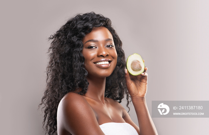 Beautiful african american woman holding avocado half